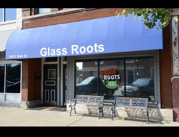 a store front with a blue awning that says glass roots