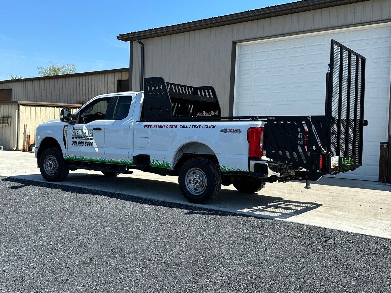 A white truck with a trailer attached to it is parked in front of a building.