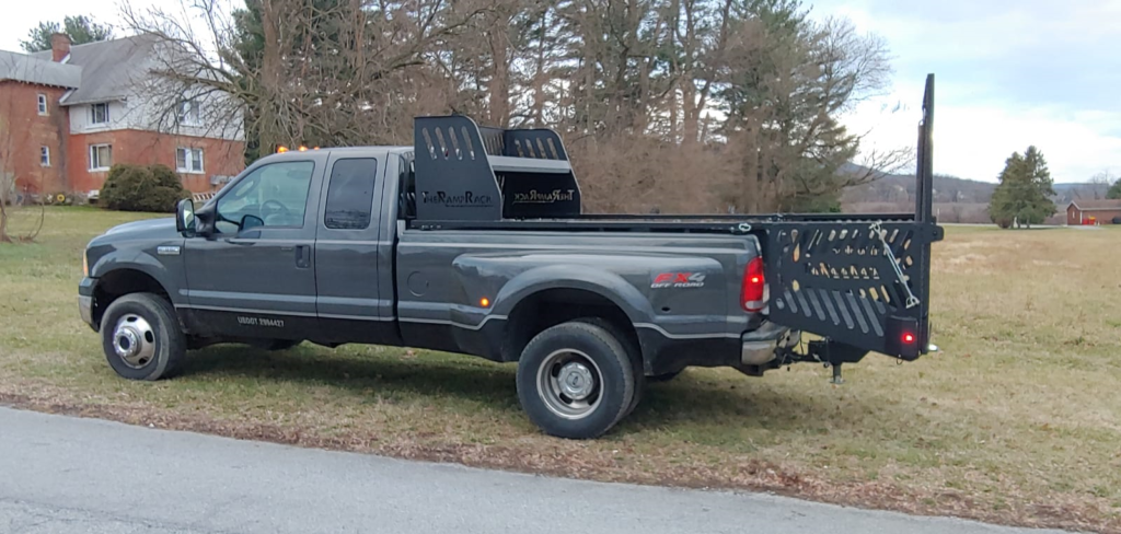 A black truck with a trailer attached to it is parked on the side of the road.