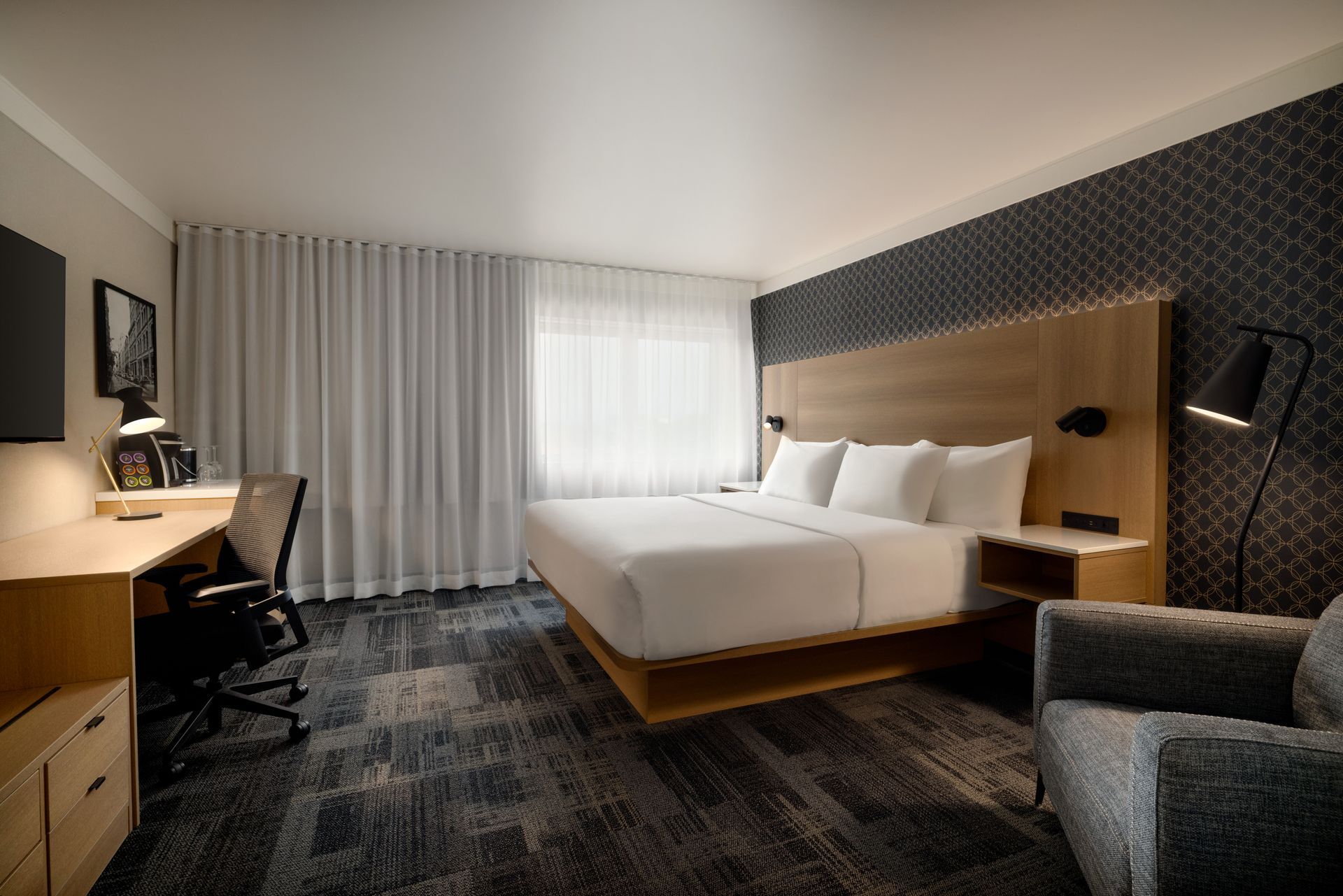 Une chambre d'hôtel avec un lit king size, un bureau, une chaise et une télévision.
