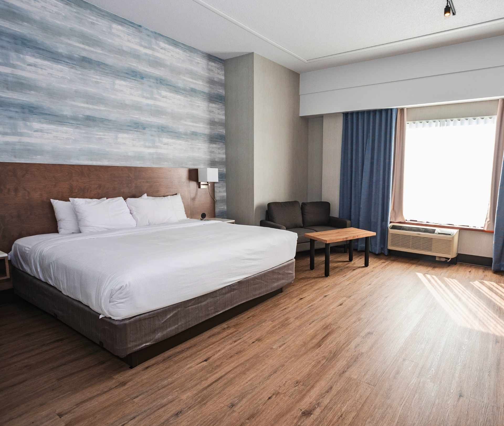 Une chambre d'hôtel avec un lit king size, une chaise, une table et une fenêtre.