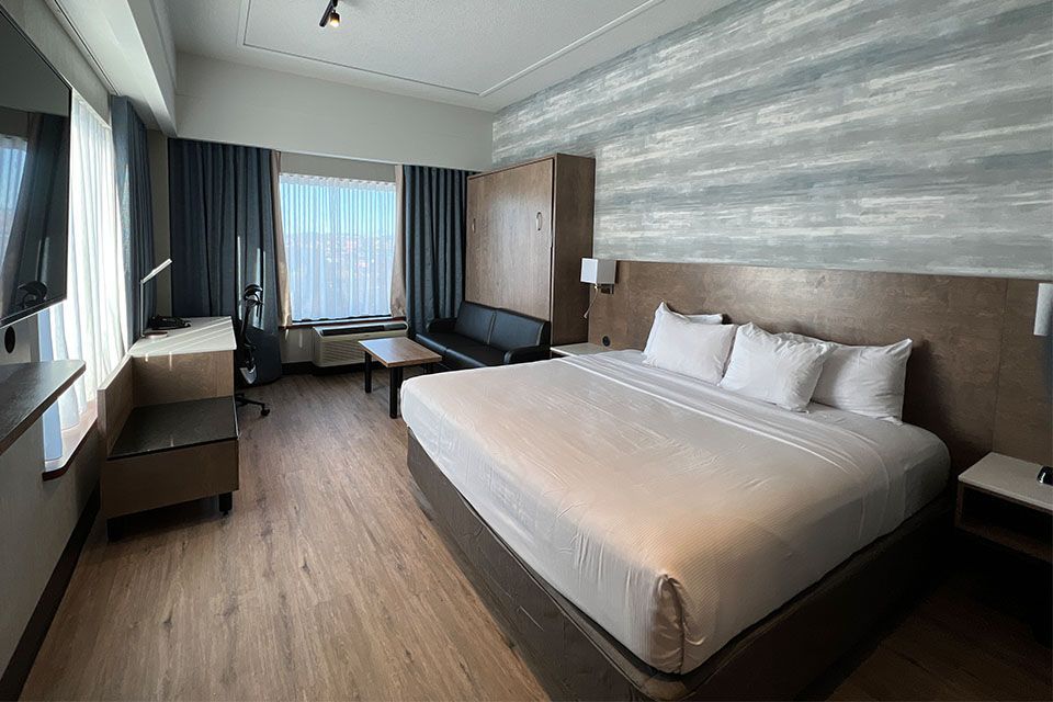Une chambre d'hôtel avec un lit king size, un canapé, un bureau et une télévision.