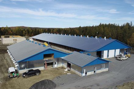 Une vue aérienne d'un grand bâtiment agricole avec des panneaux solaires sur le toit.