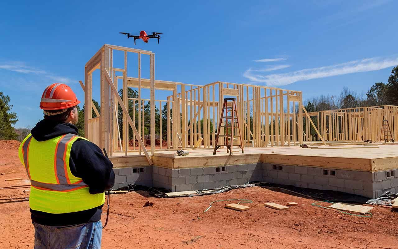 un ouvrier du bâtiment inspecte un bâtiment en construction à l'aide d'un drone.