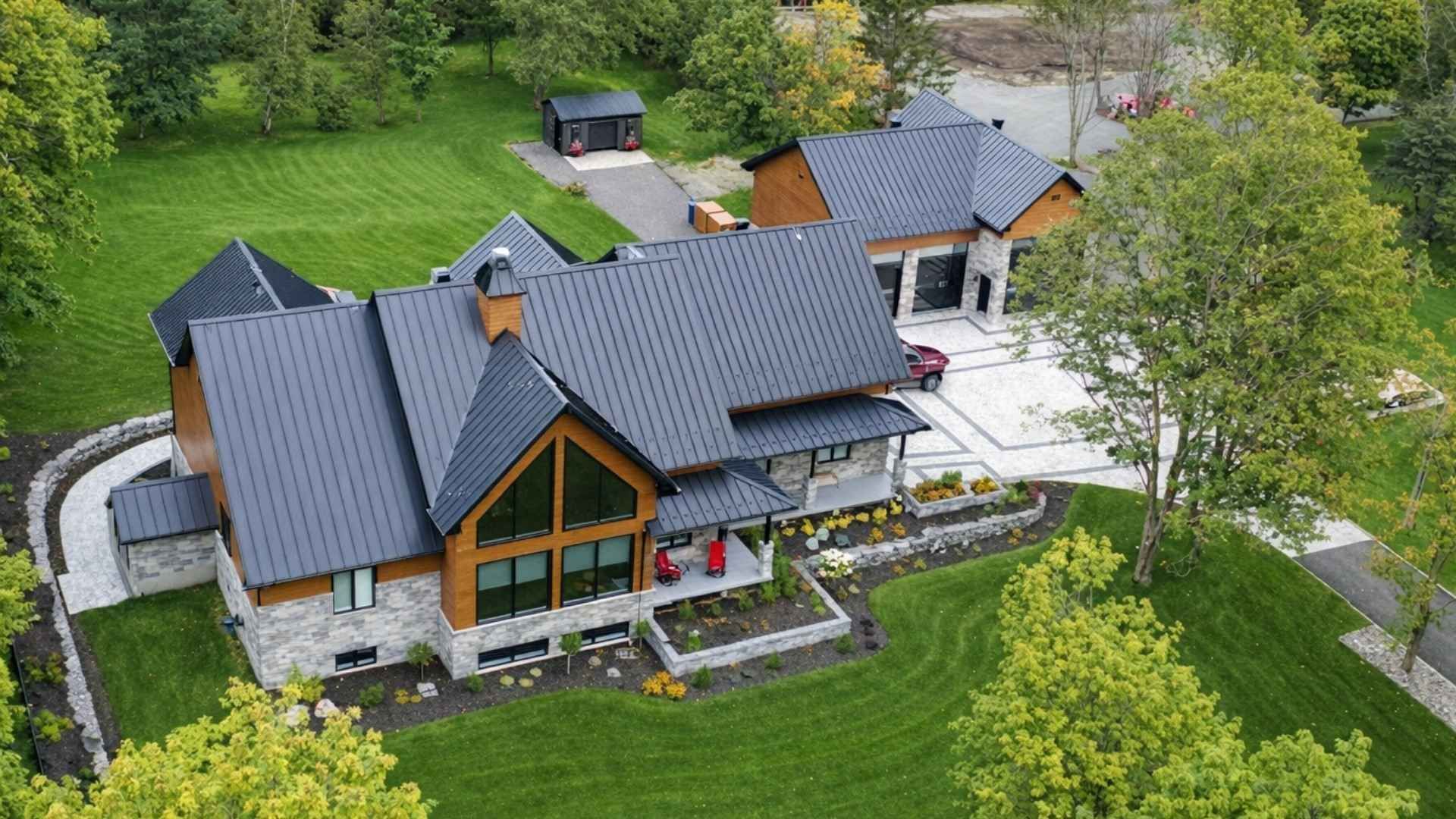 Maison de prestige moderne avec toit gris, éléments en bois et pelouse verdoyante.