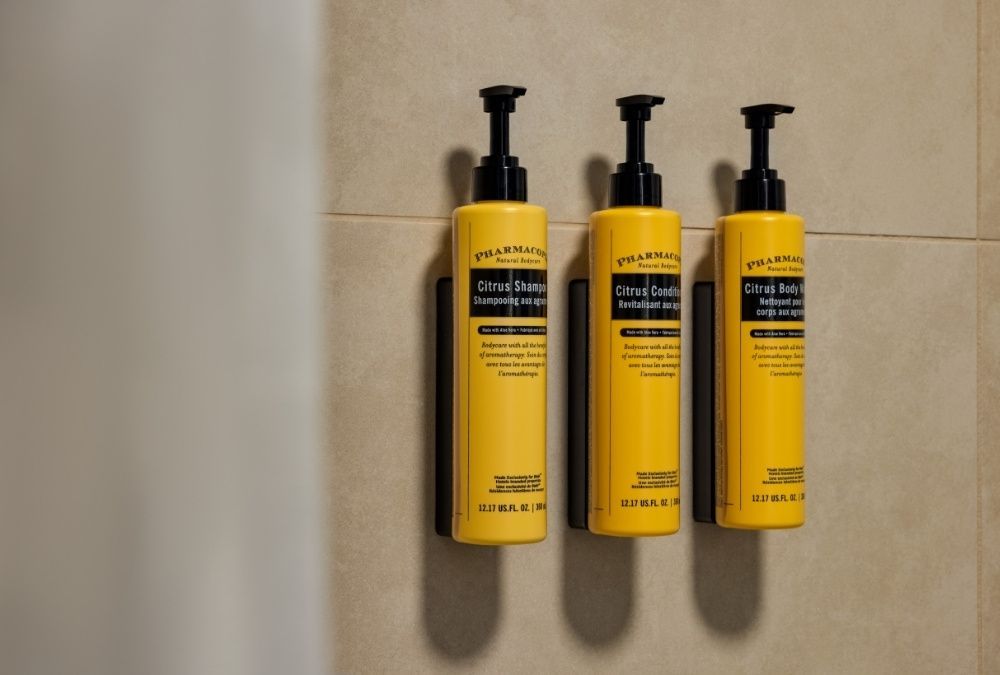 Trois bouteilles jaunes de shampoing sont accrochées au mur