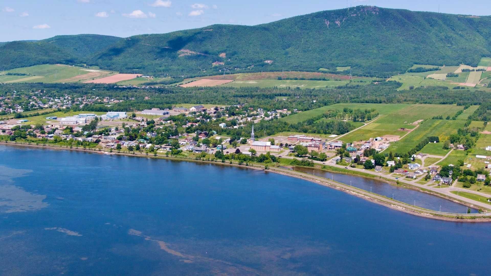 Municipalité de Carleton-sur-Mer avec une eau bleue, une plage de sable et des collines.
