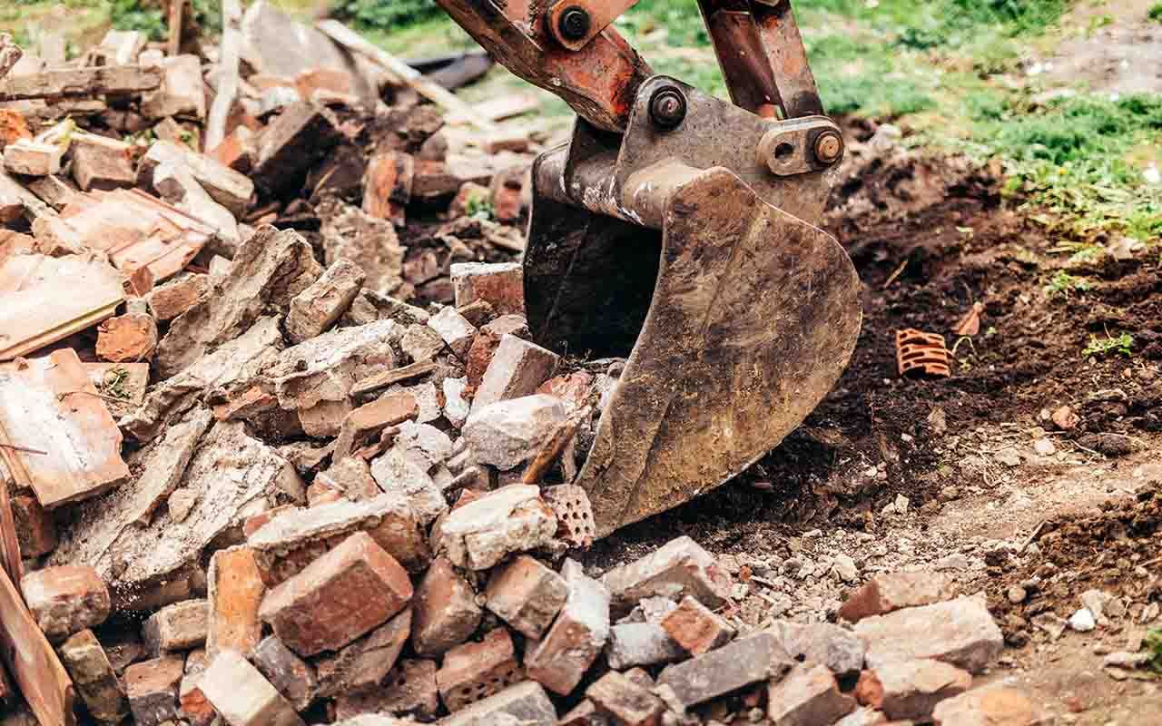un bulldozer récupère des briques du sol.