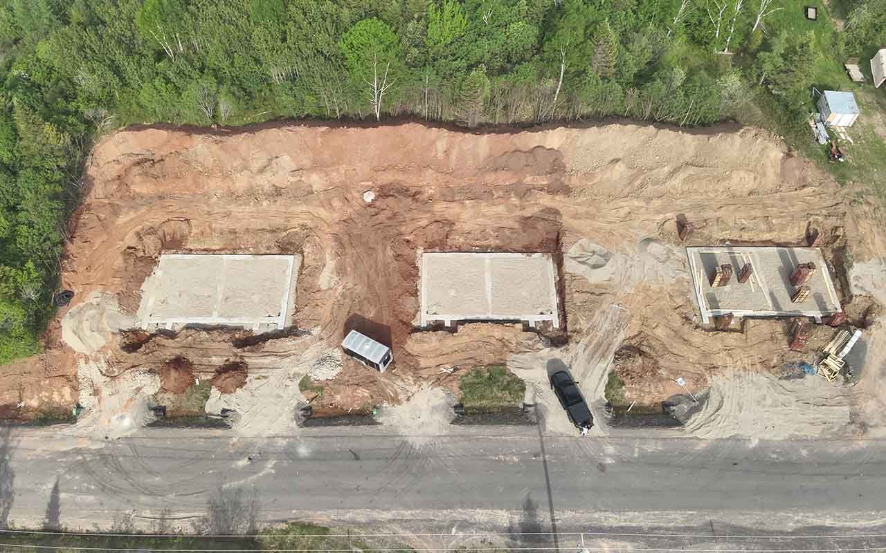 une vue aérienne d'un chantier de construction en fondation à côté d'une route.