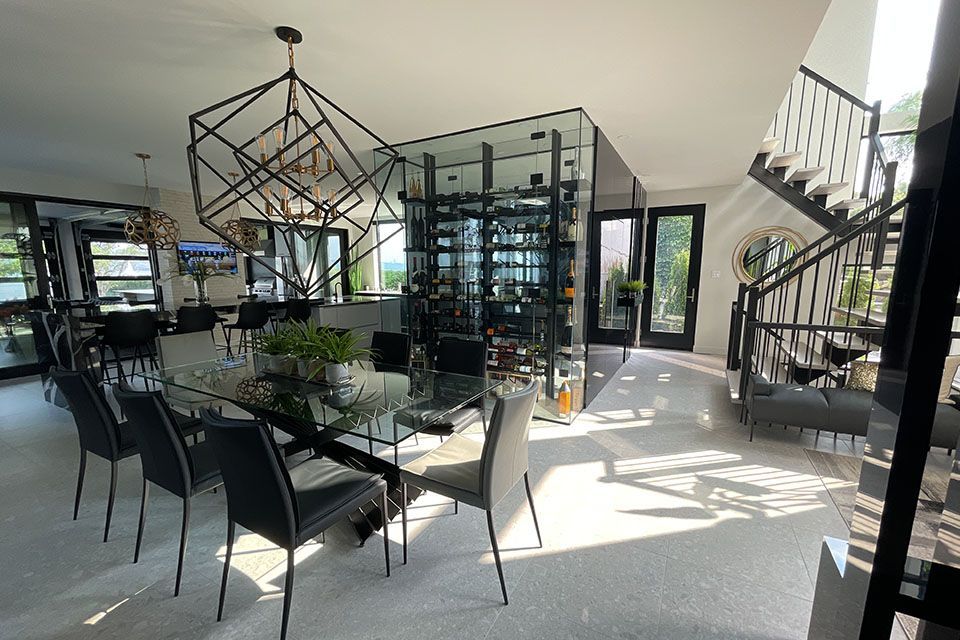 Une grande salle à manger avec une table et des chaises en verre et un escalier.