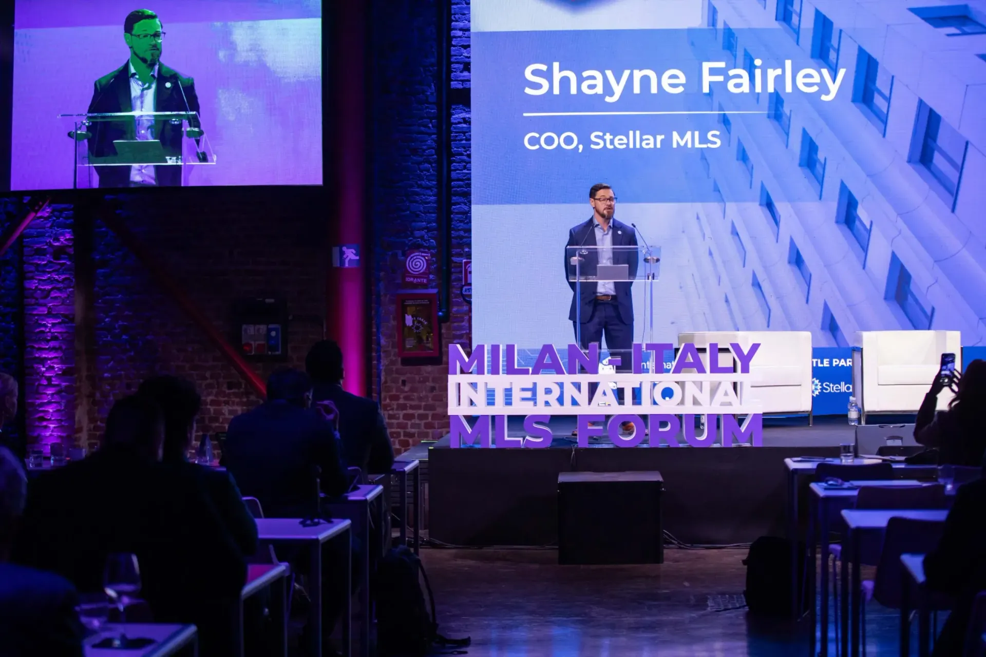 Shayne Fairley speaking at a conference podium; 