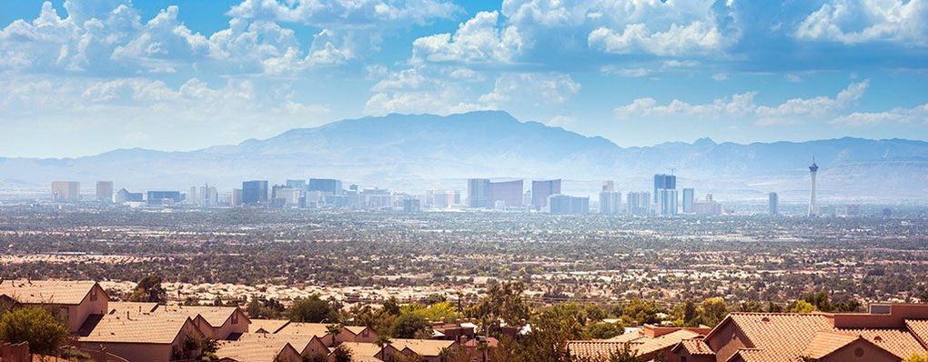 An aerial view of a Las Vegas neighborhood with the skyline and mountains in the background.