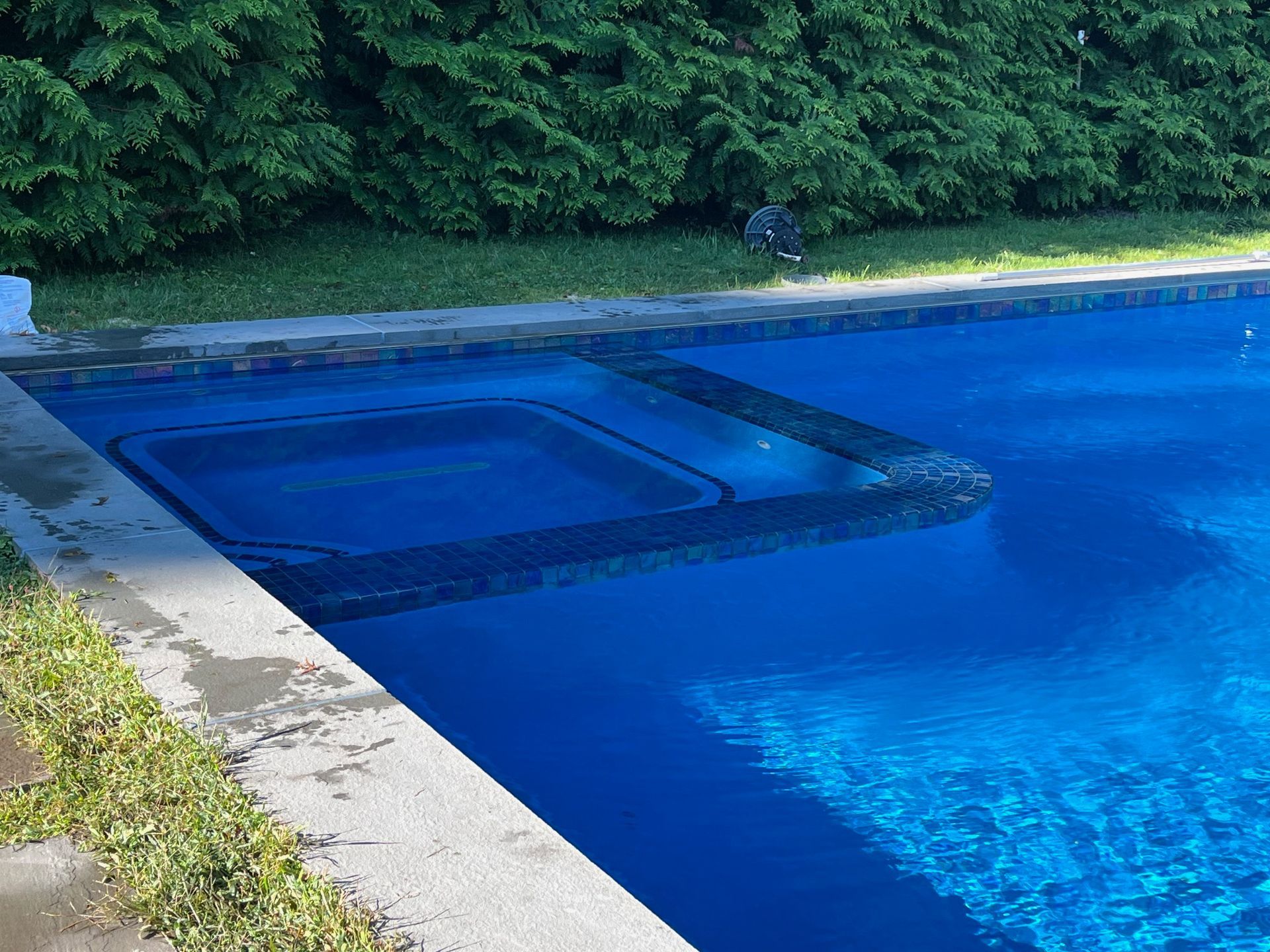 A large swimming pool with a hot tub in the middle of it.