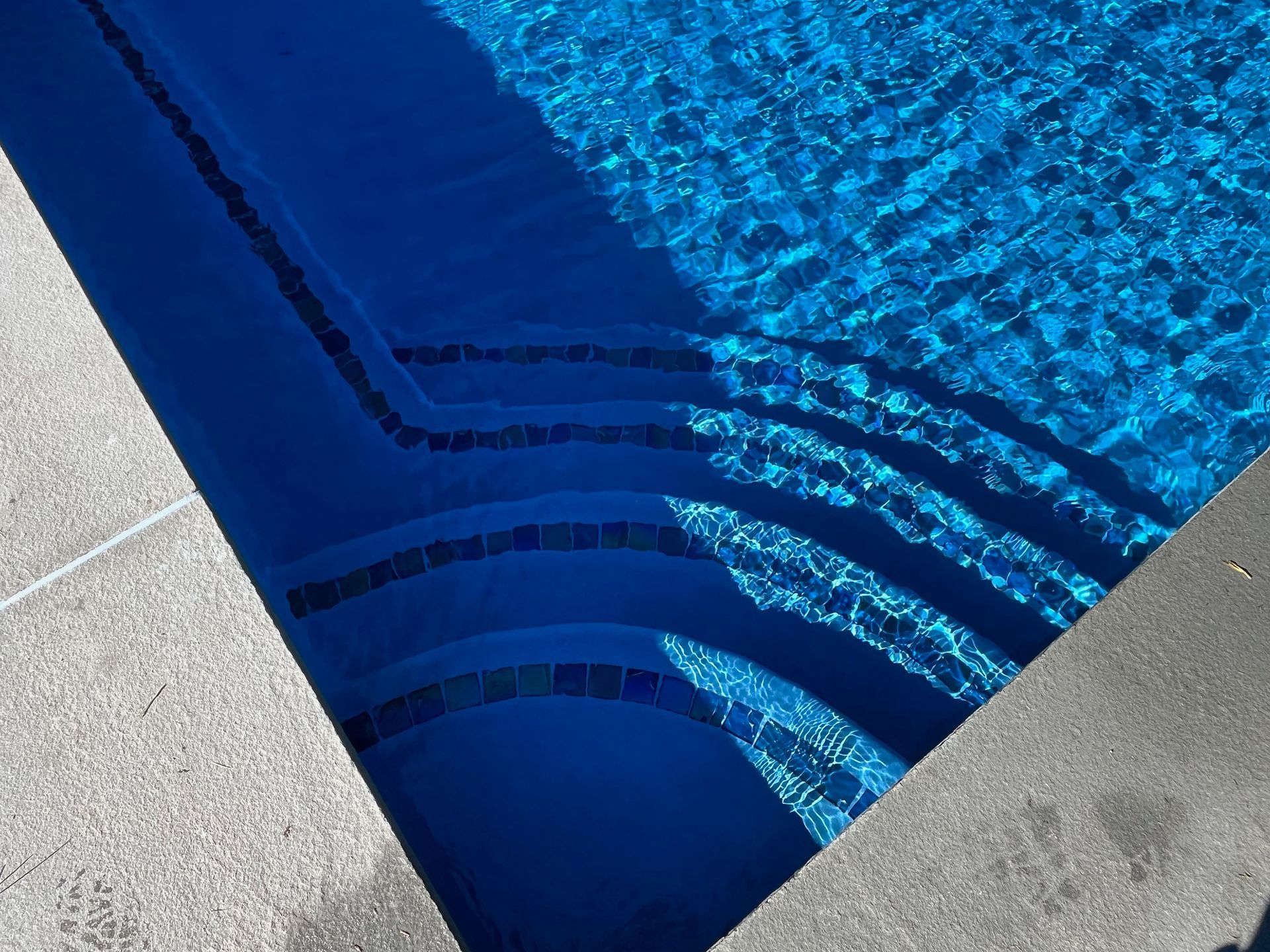 A close up of a swimming pool with blue water and steps.