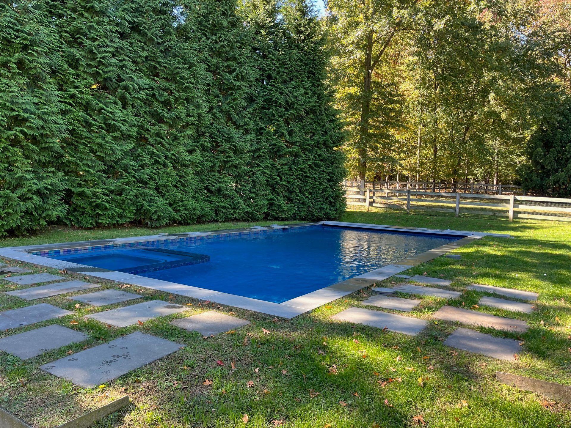 There is a large swimming pool in the middle of a lush green yard.