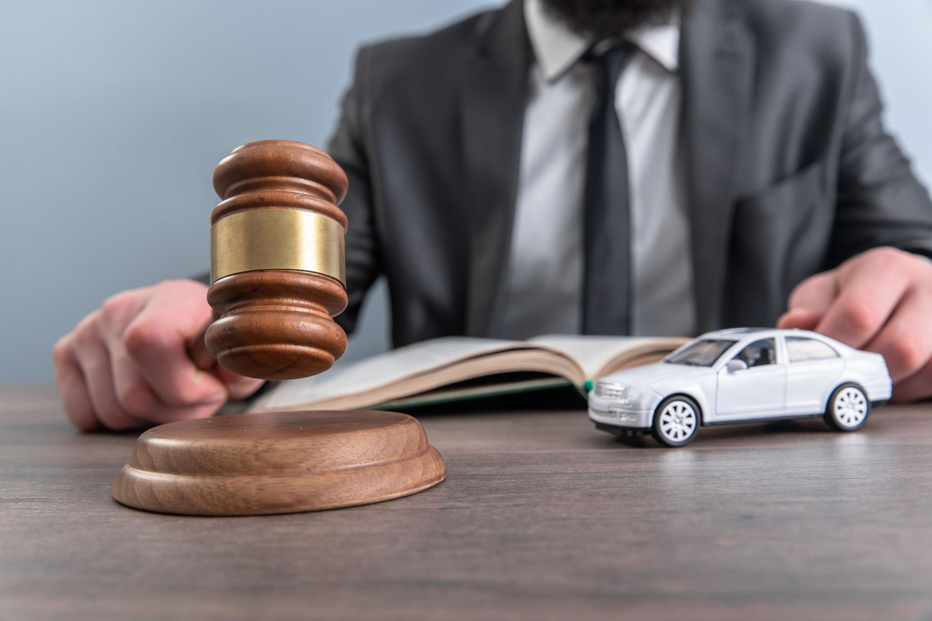 Lawyer with gavel beside toy car and contract on desk, suggesting an auto accident legal case
