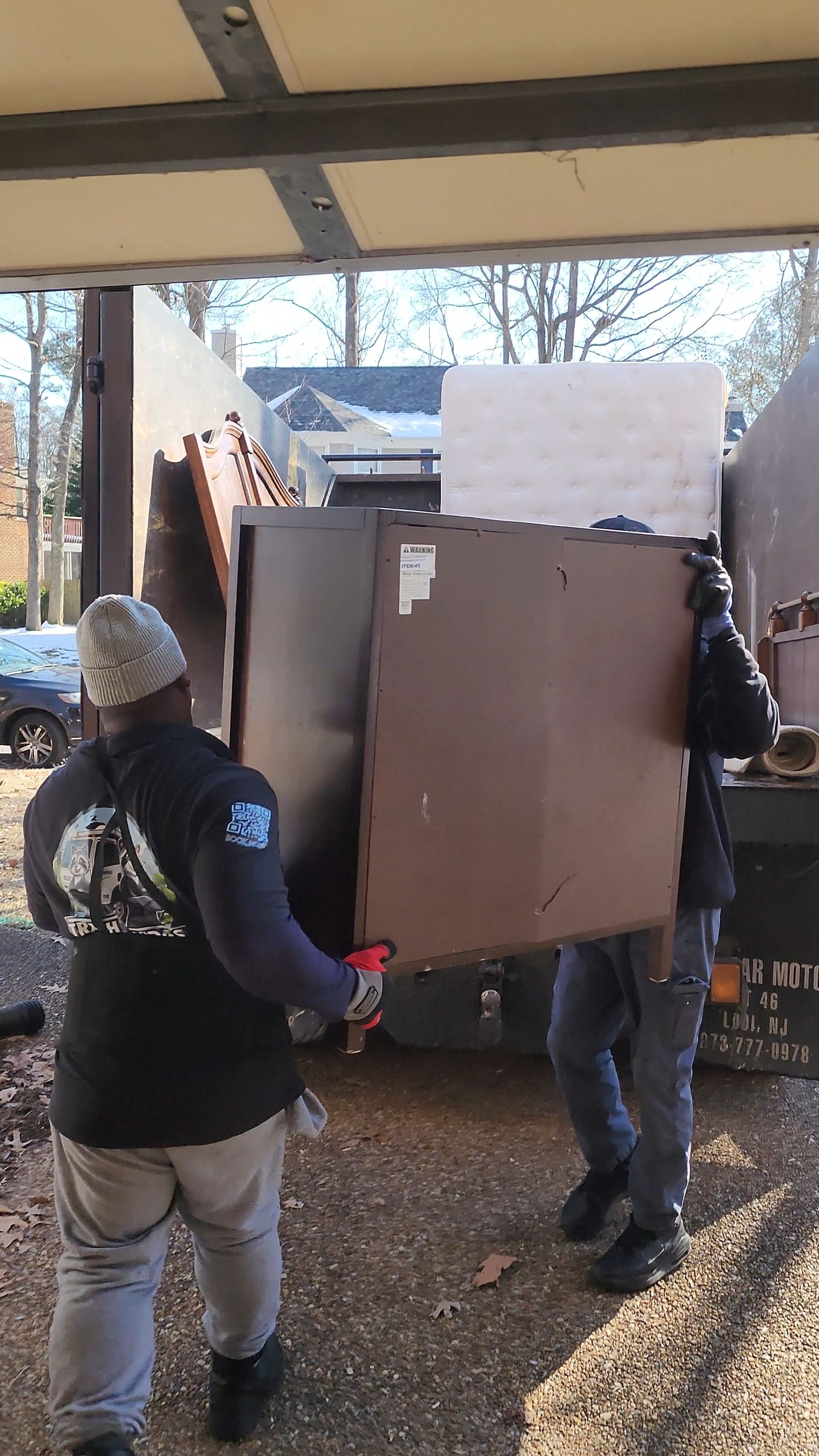 Two men are carrying a large piece of wood into a truck.