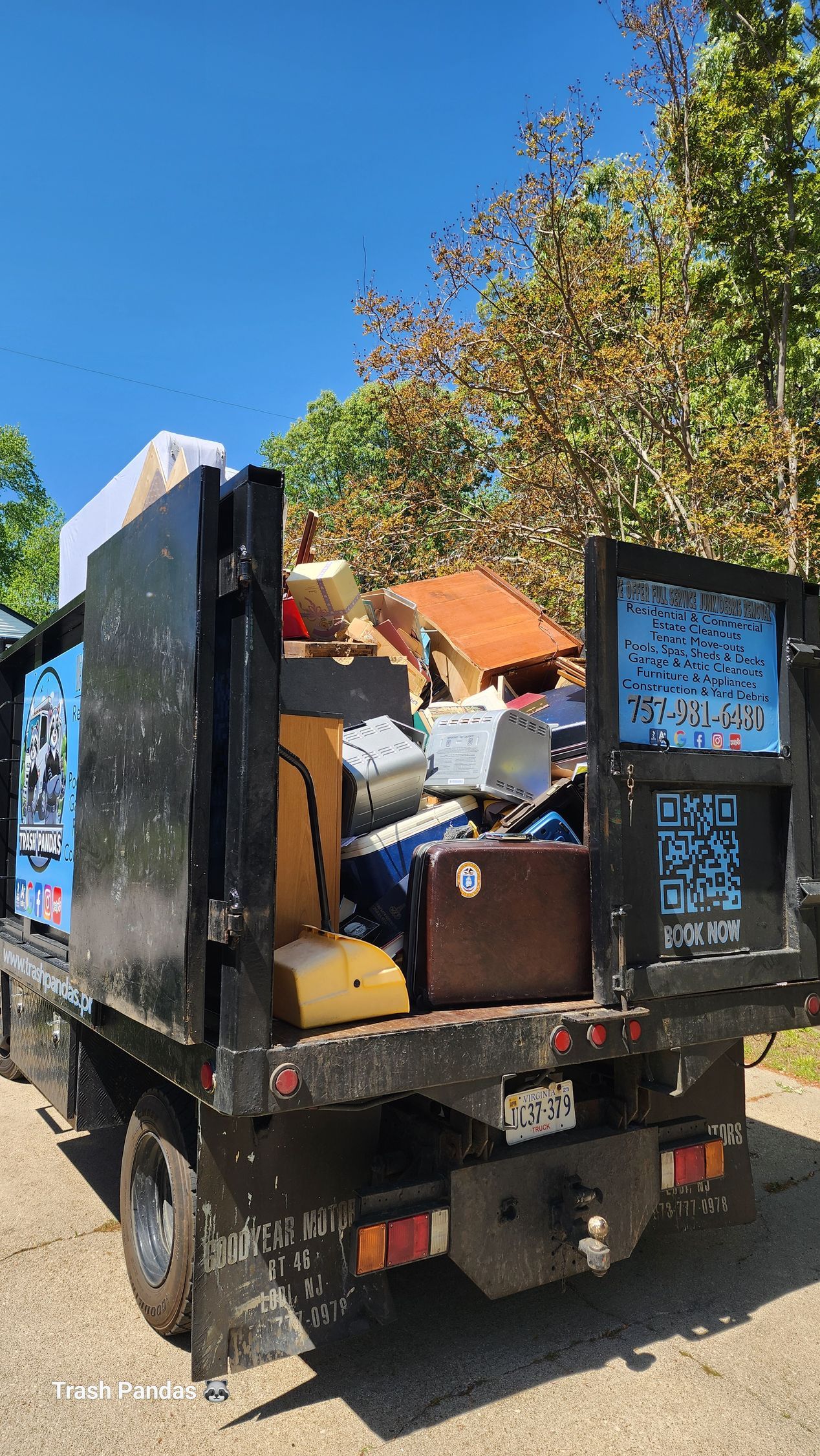 A dump truck filled with junk is parked on the side of the road.