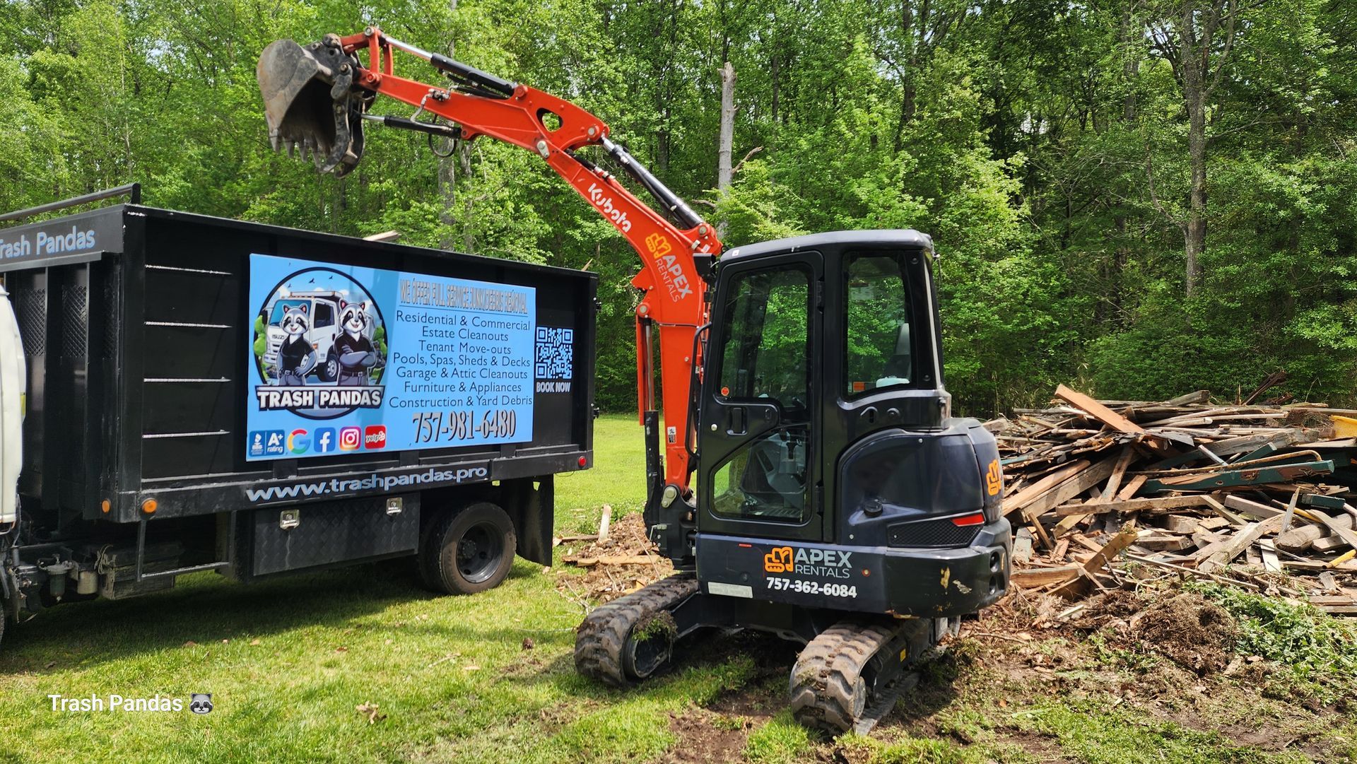 A small excavator is digging a hole in the ground next to a dumpster.