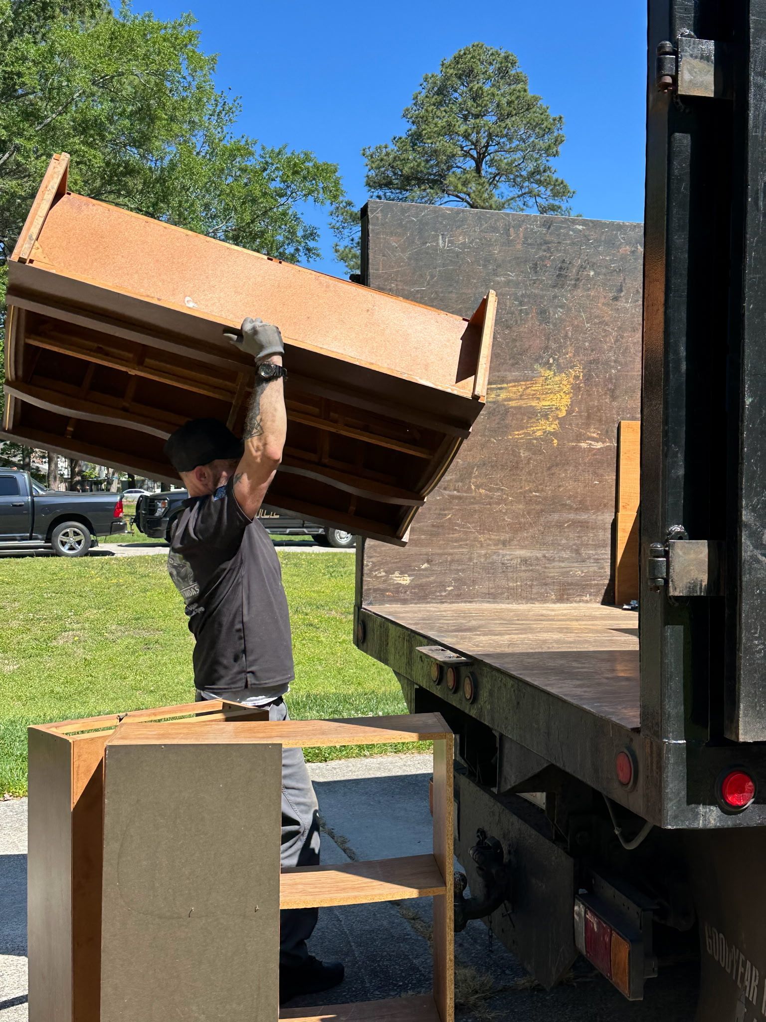 A man is carrying a large piece of wood on top of a truck.