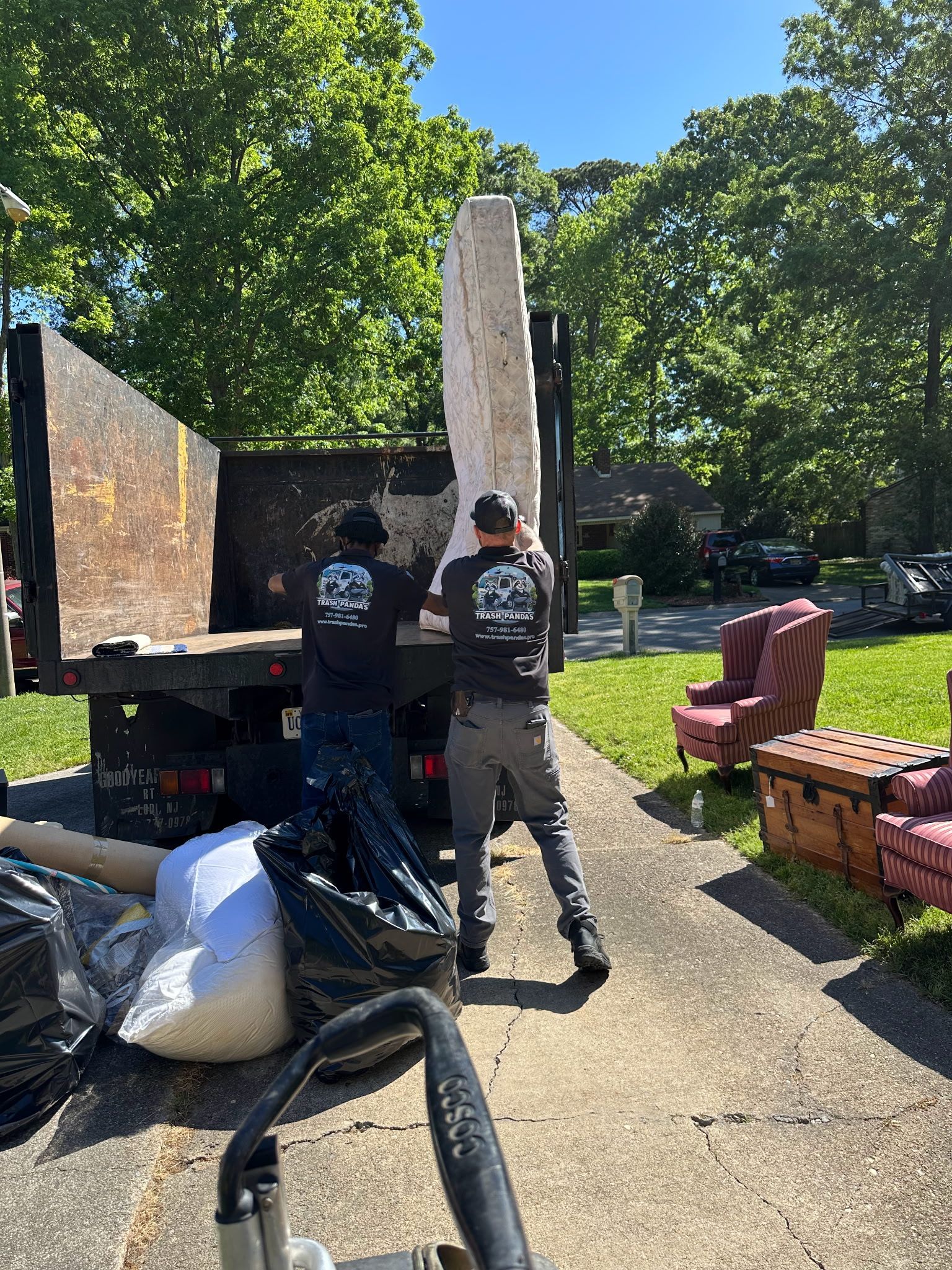 Two men are loading a large rock into a dumpster.