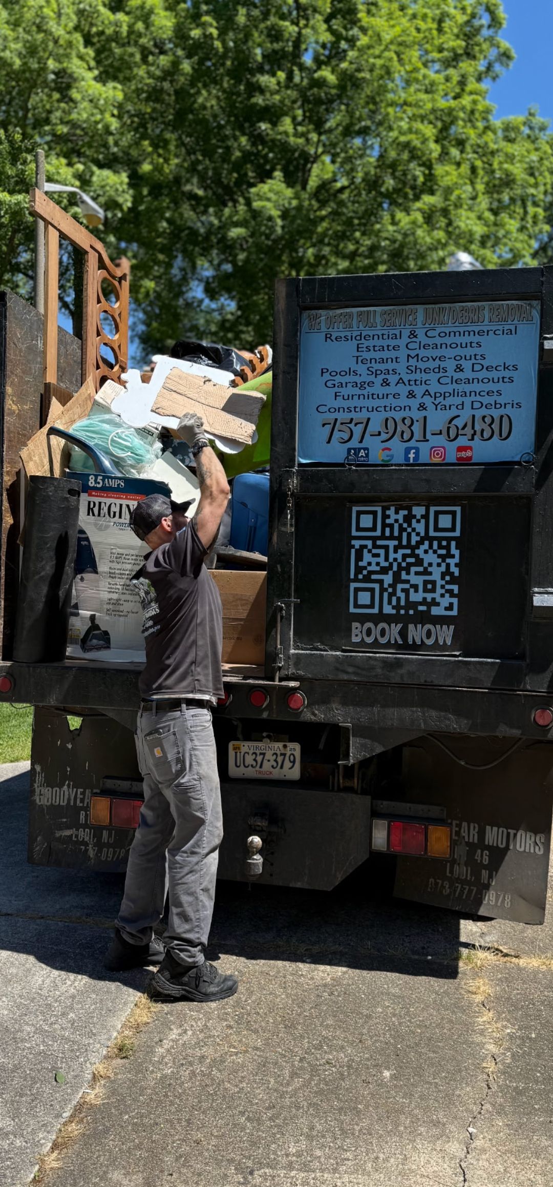 A man is standing in front of a dumpster filled with trash.
