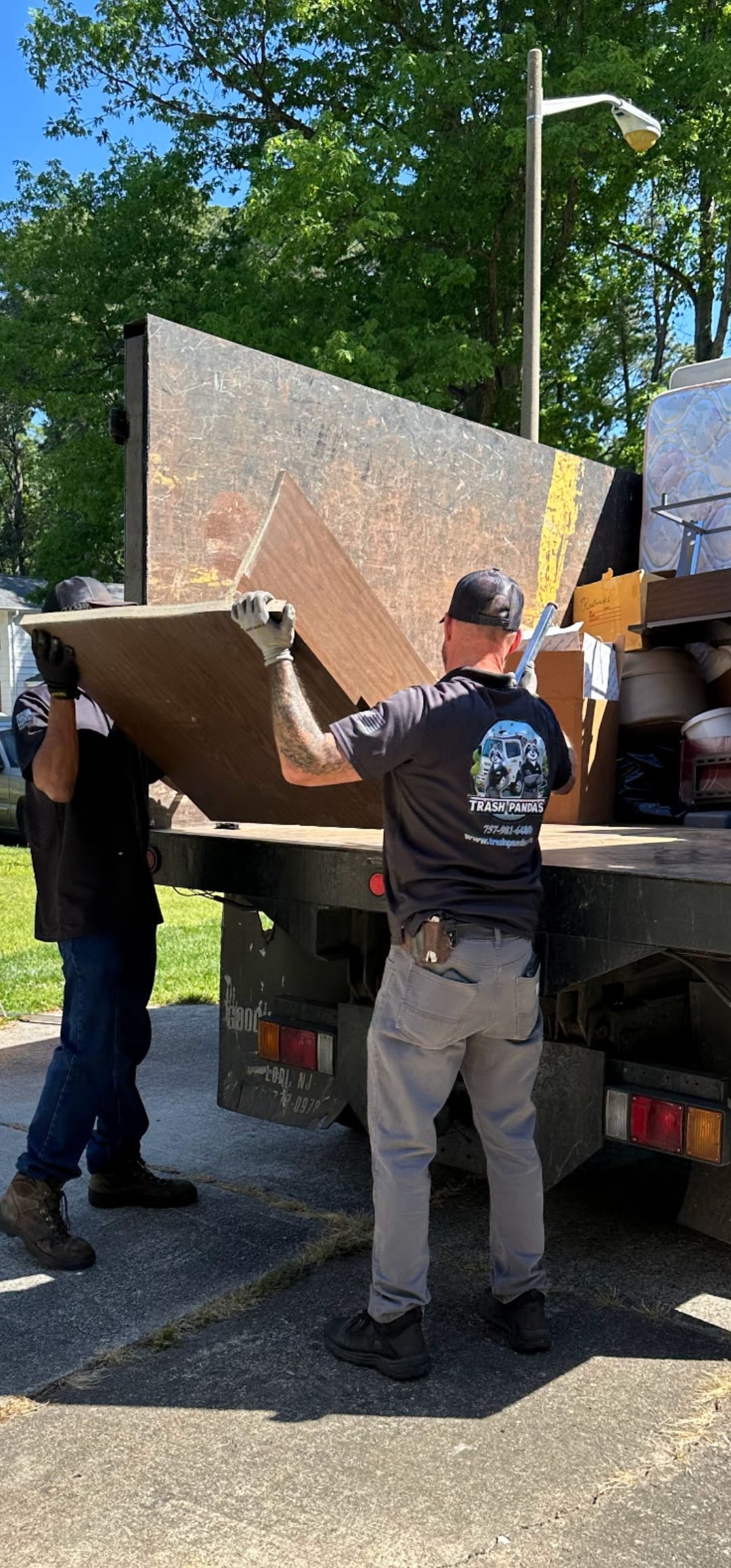 A man is standing in front of a dumpster filled with junk.