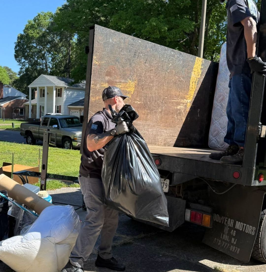 A man is loading garbage into a dumpster.