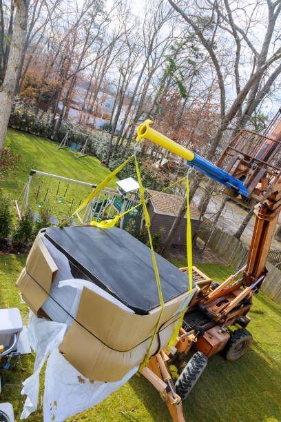 A hydraulic boom truck is lifting a hot tub on a backyard, showcasing expert hot tub removal.