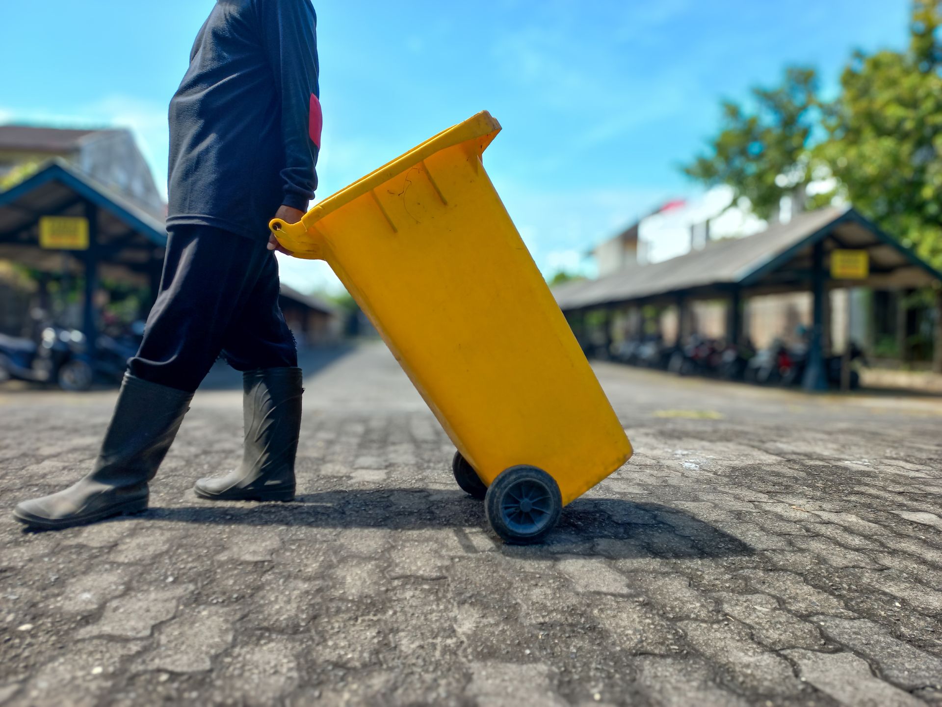 Trash removal crew member handling container during residential junk pickup. Trash removal crew member handling container during residential junk pickup.