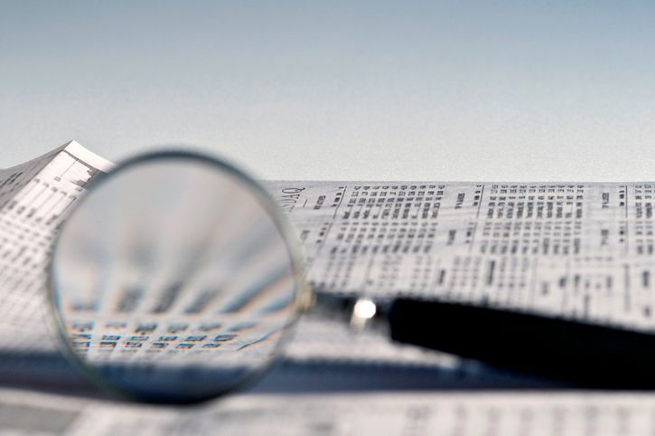 A magnifying glass is sitting on top of a pile of papers.