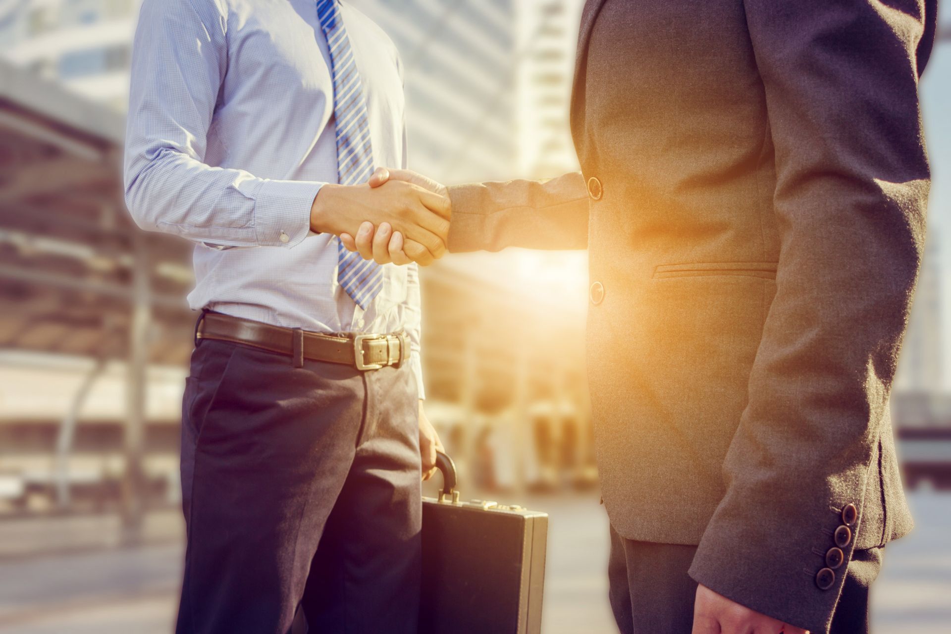 Two businessmen shaking hands in front of a building.