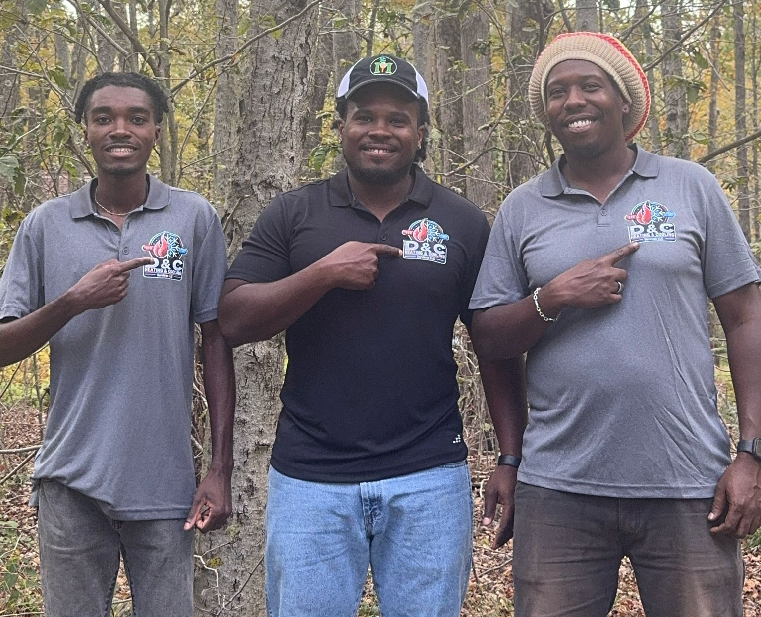 Three people in front of trees point to logos on their shirts.