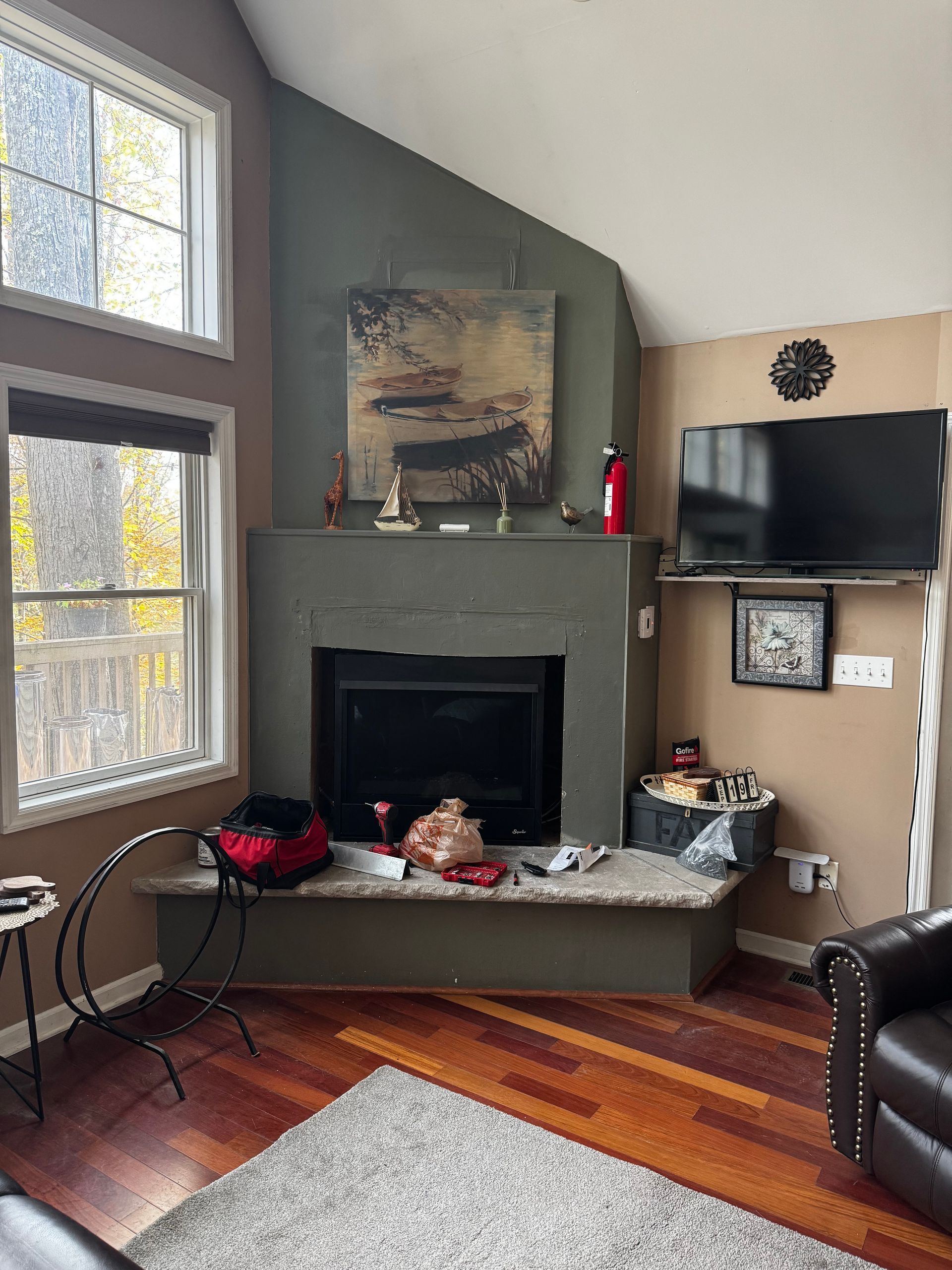 Living room with fireplace, TV, and windows, featuring a green and brown color scheme.