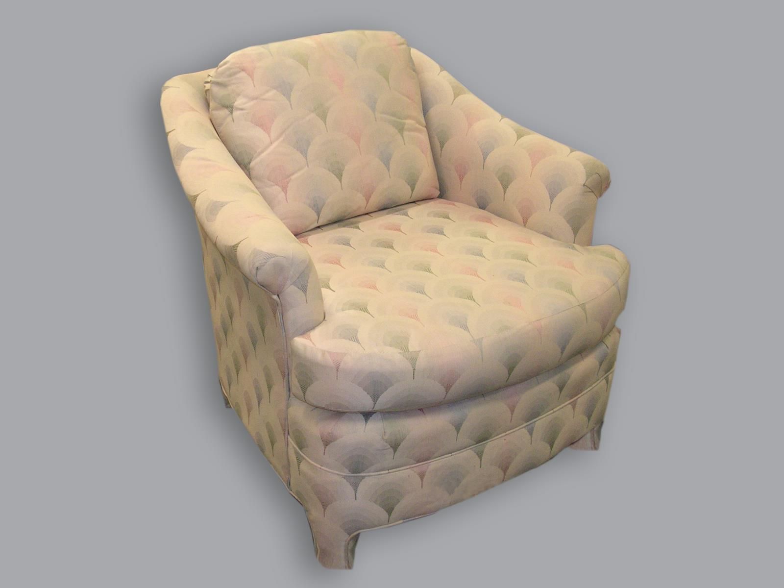An upholstered armchair featuring a pale, repeating scalloped or fan pattern in soft shades of pink, blue, and cream.