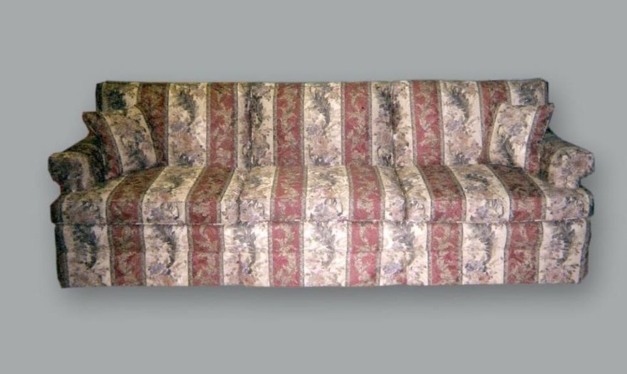 A three-cushion sofa featuring a striped fabric with floral patterns in shades of red, beige, and dark green.