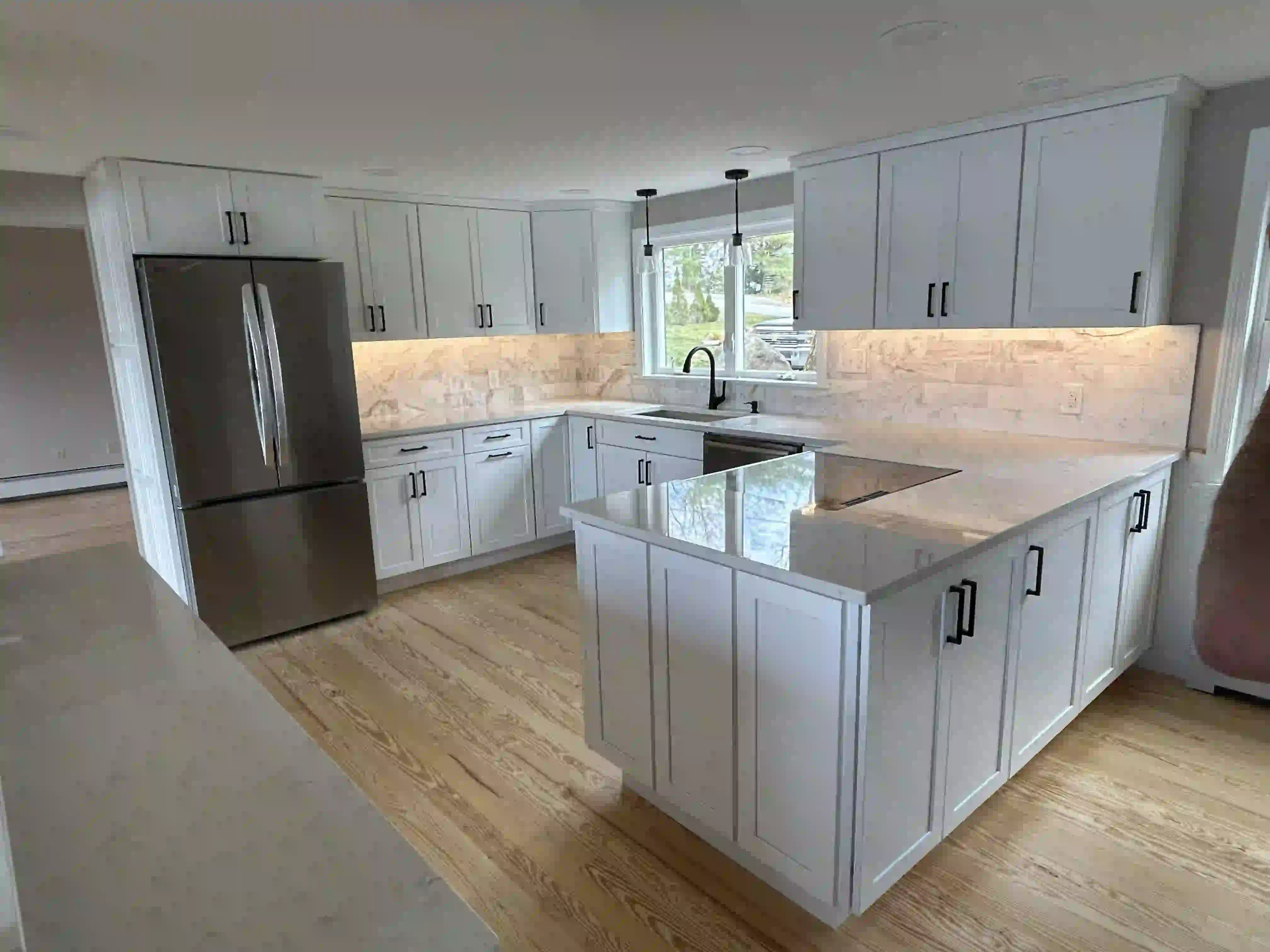 Wooden deck attached to a house with stairs, black railing, and support posts over a gravel area.