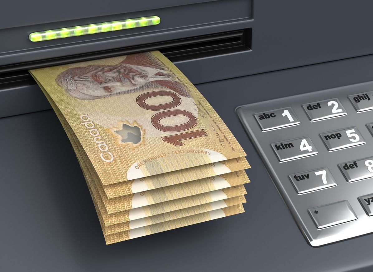 A stack of canadian 100 dollar bills coming out of an atm