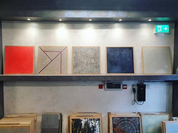 Square boards on shelves displaying different effects on plastering