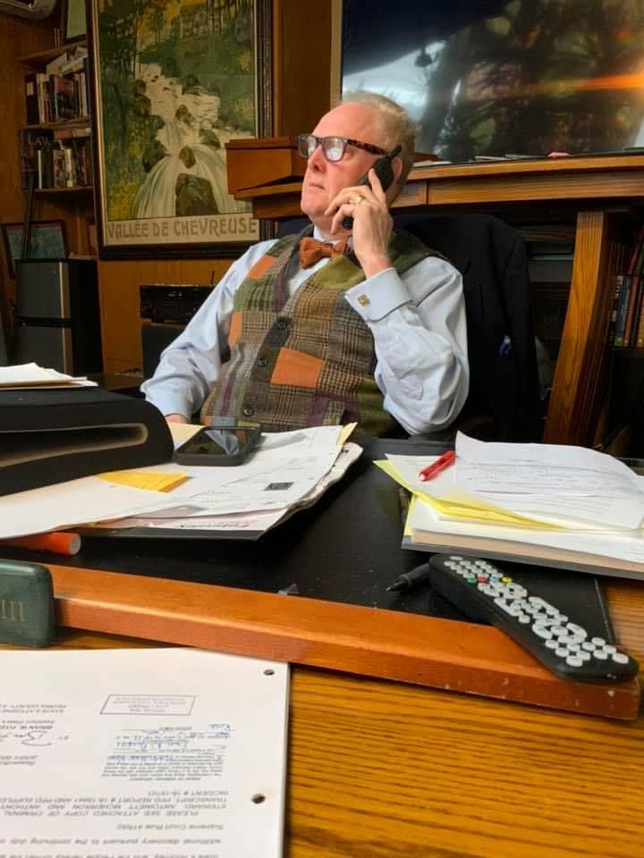 A man is sitting at a desk talking on a cell phone