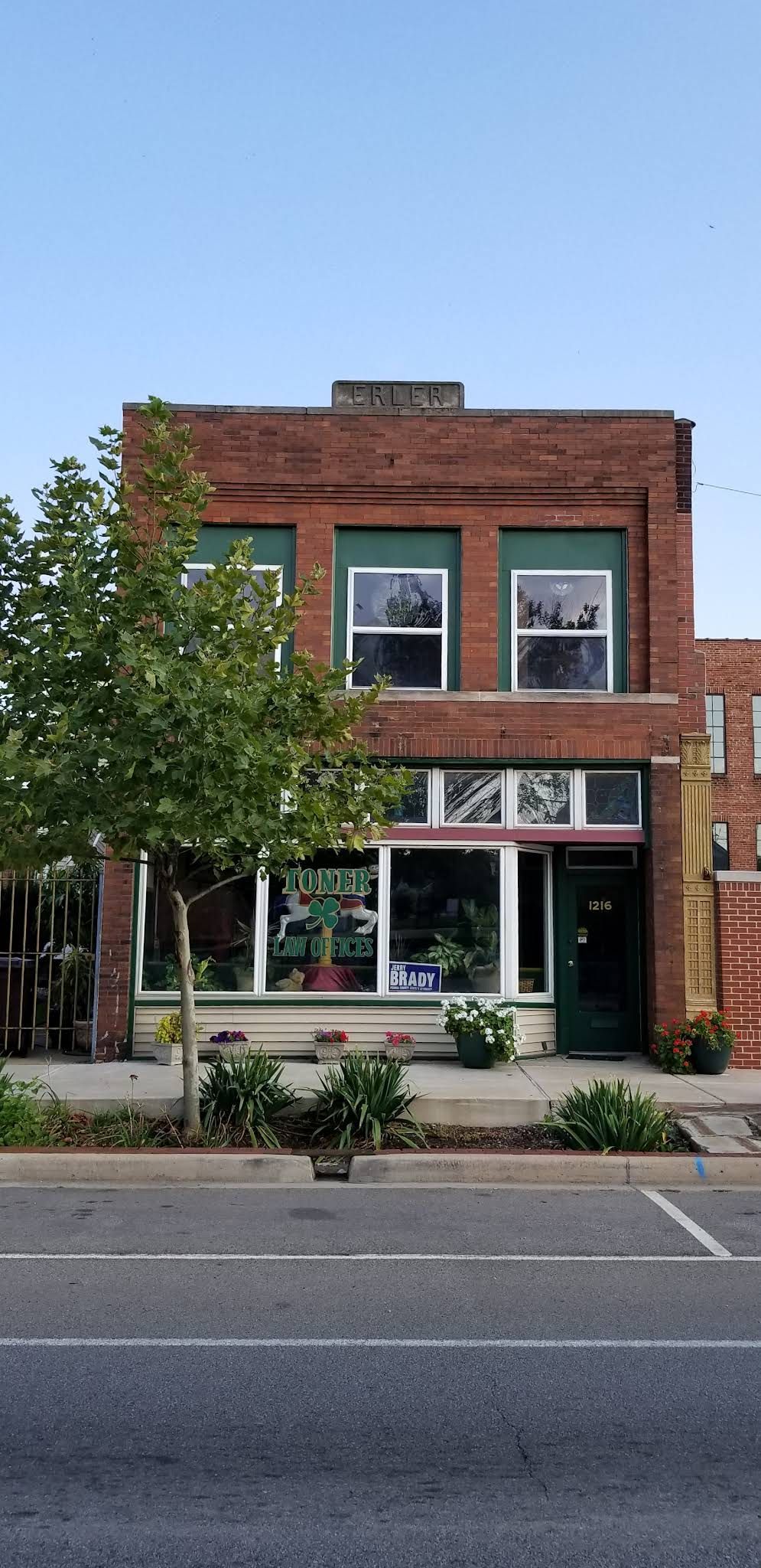 A large brick building with a lot of windows and a tree in front of it.