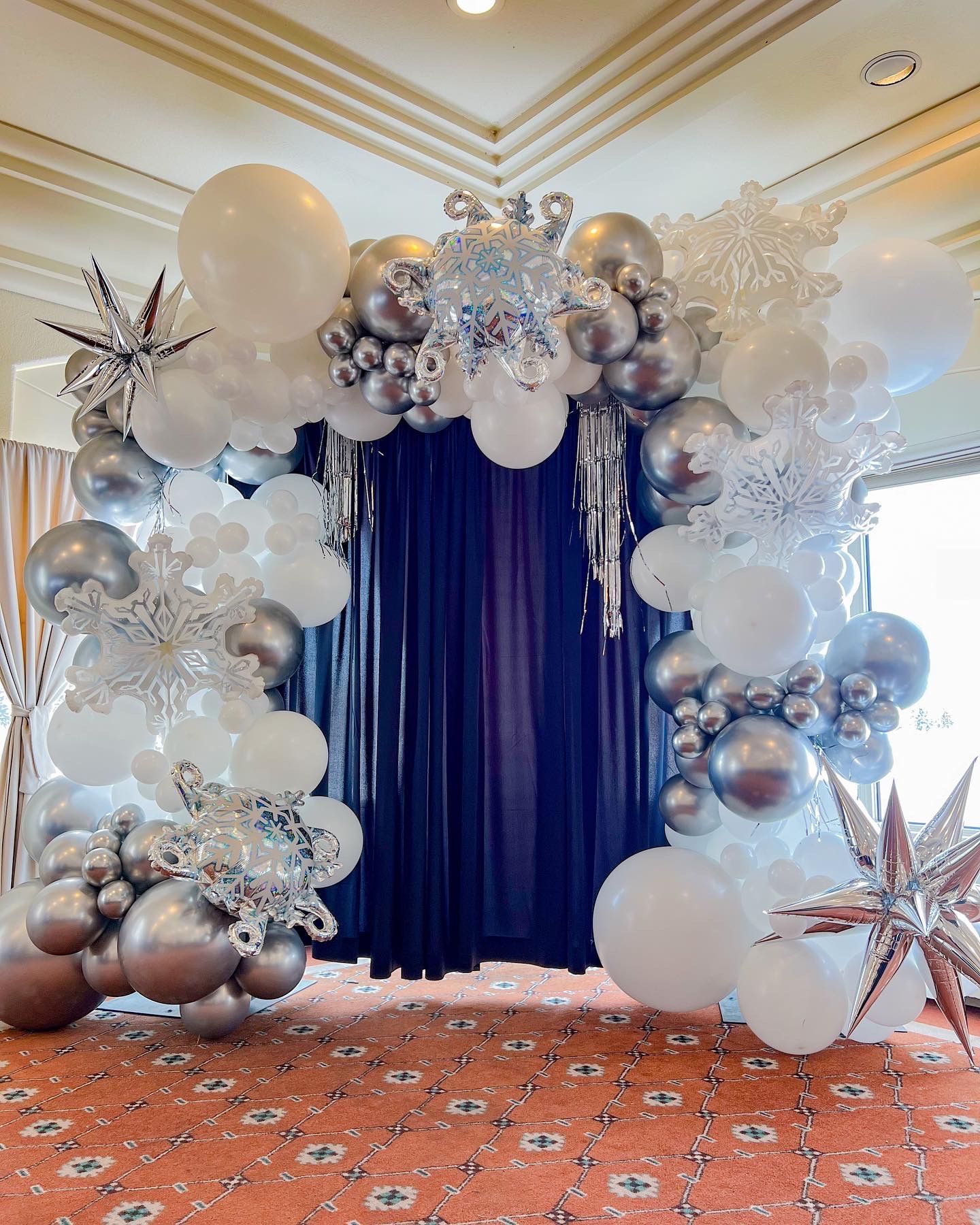 A room decorated with white and silver balloons and snowflakes.