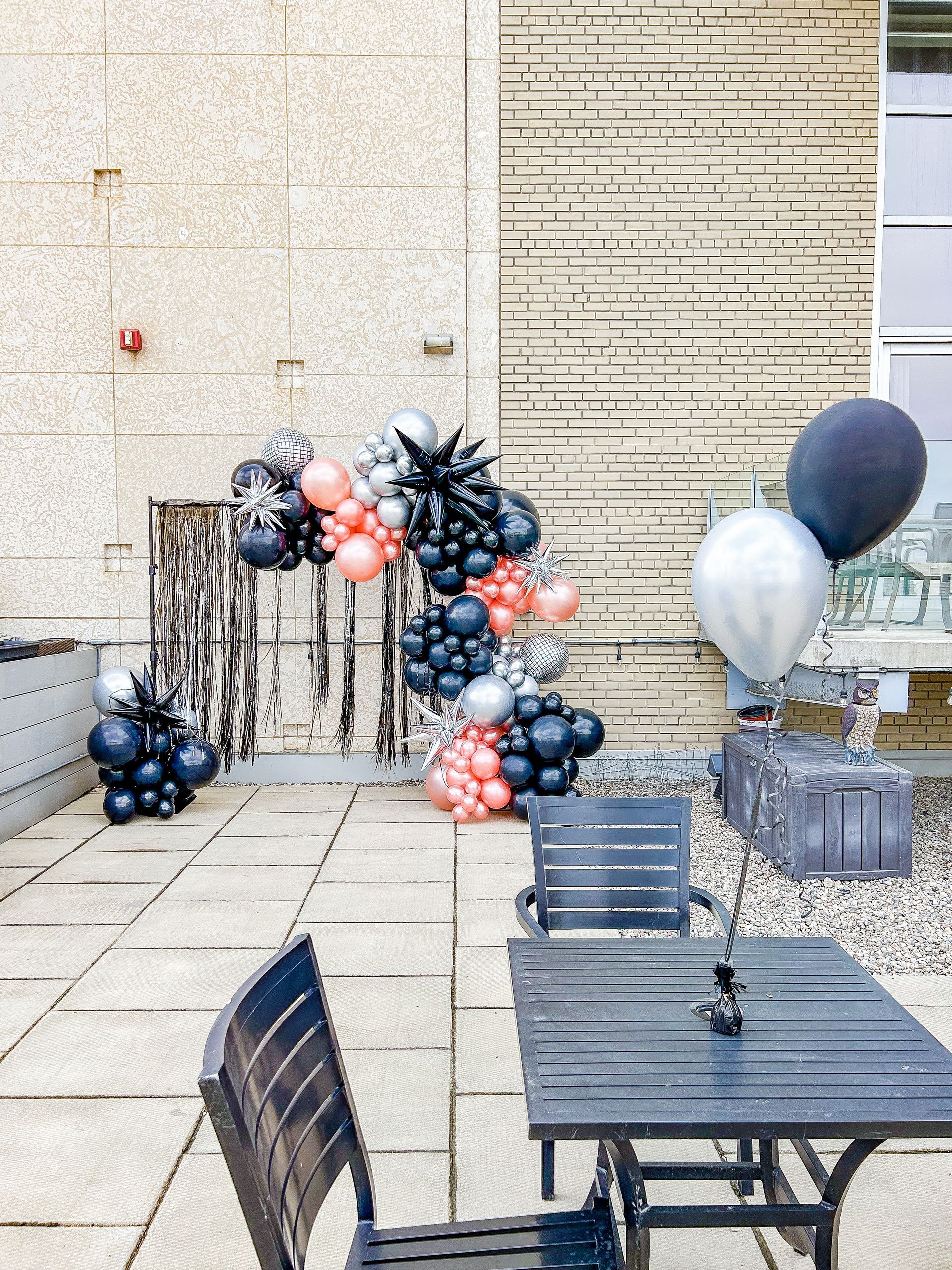 A table and chairs on a patio with balloons in the background.