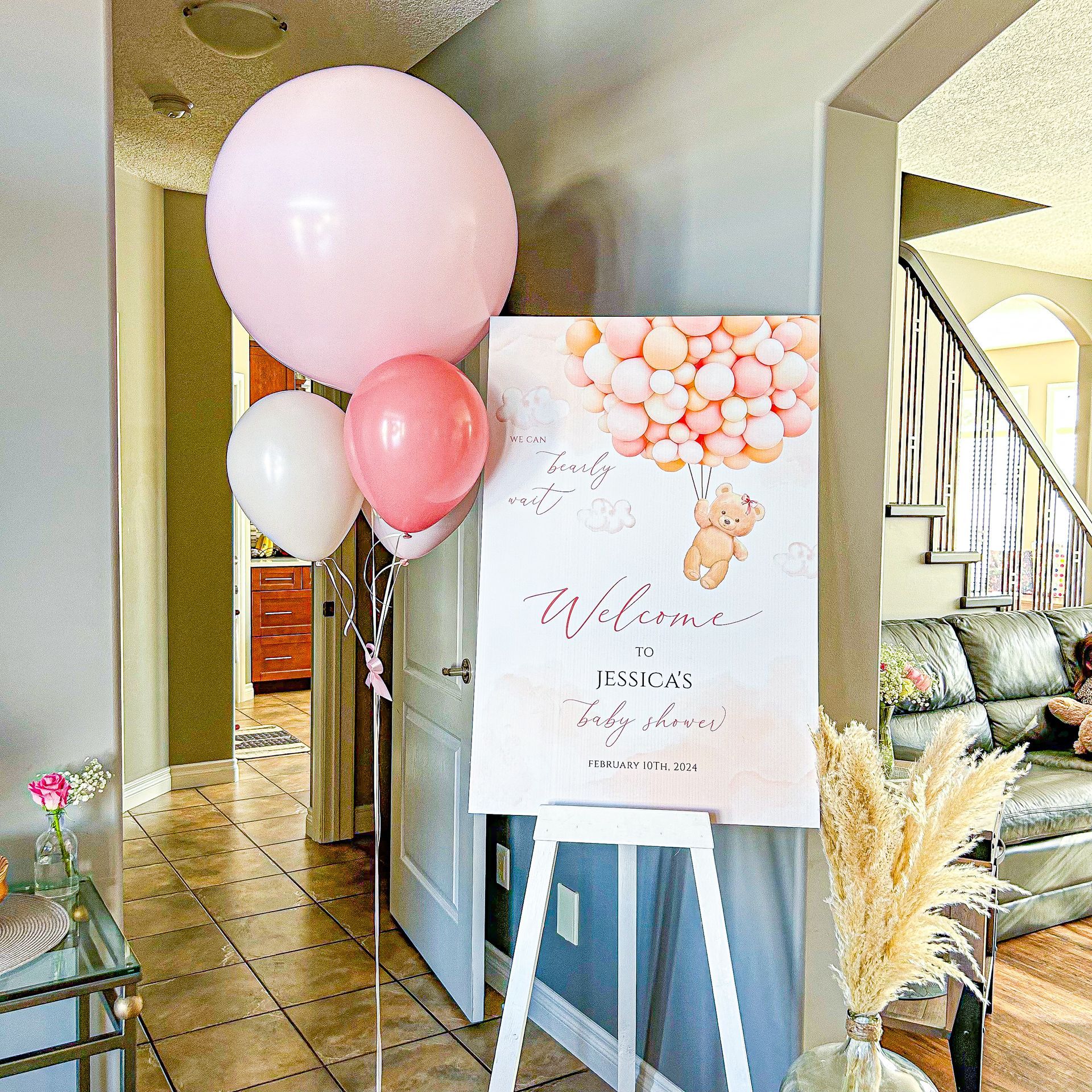 A welcome sign with balloons and a teddy bear on it