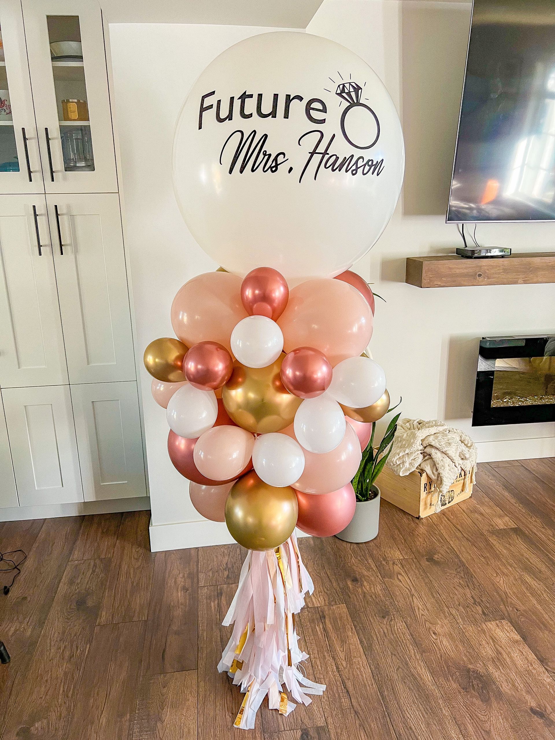A bunch of balloons are sitting on a wooden floor in a living room.