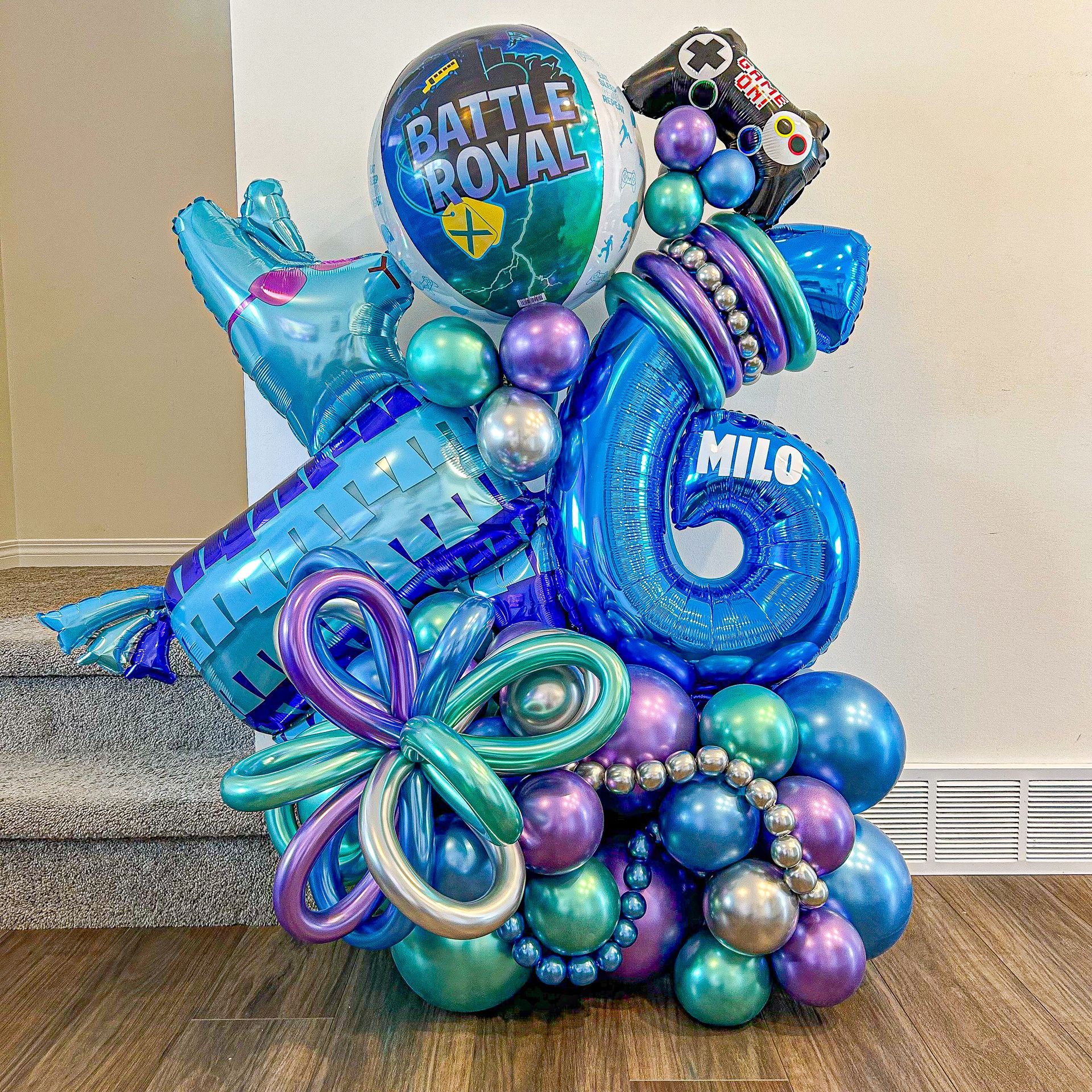 A bunch of blue and purple balloons are sitting on a wooden floor.