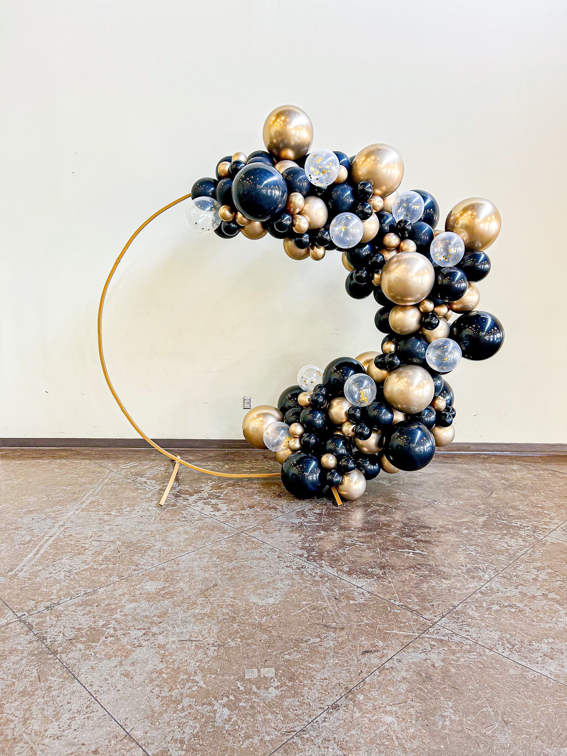 A wreath made of black and gold balloons is sitting on a table.
