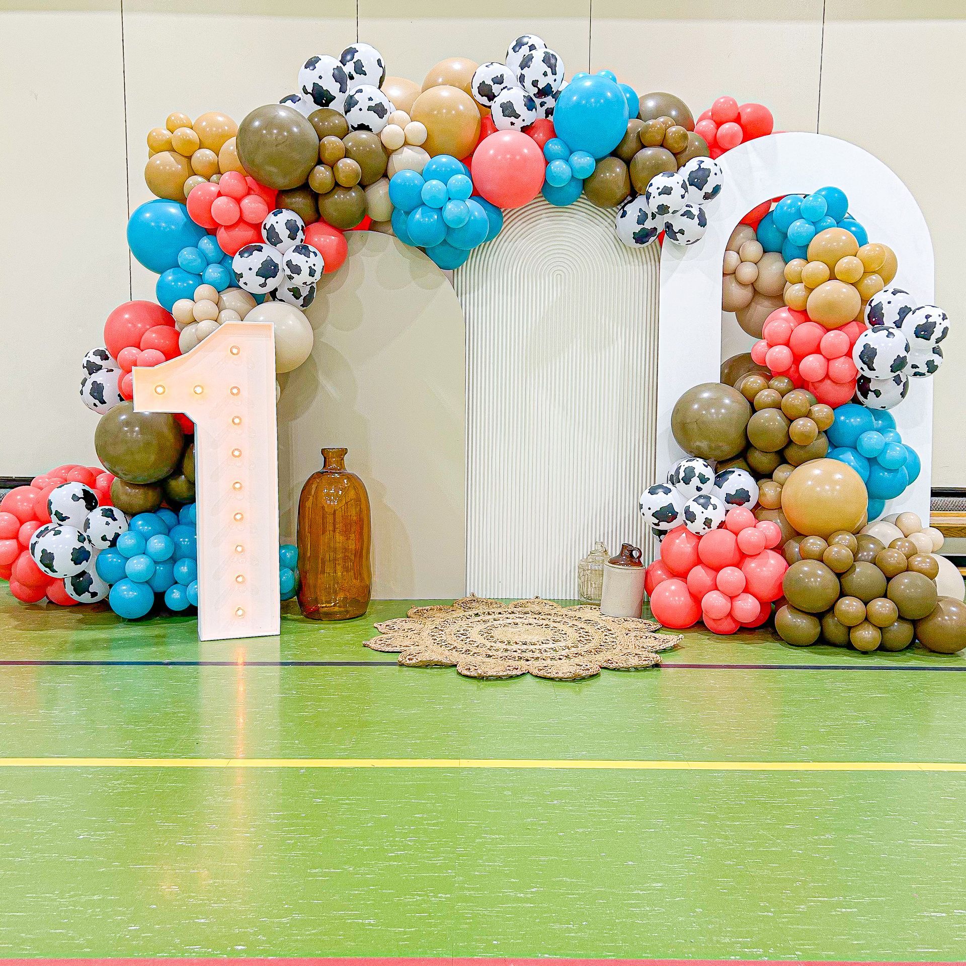 A number 1 is surrounded by balloons on a green floor.