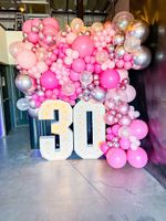 A wall of pink and silver balloons with the number 30 in the middle.