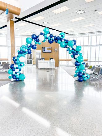 A large arch made of blue and white balloons in a room.